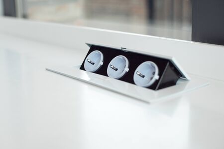 Pop-up internal socket in a white table, charging for phones and devices.の写真素材