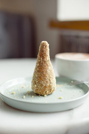 Delicious dessert anthill with dates and crumbs on a mint dessert plate with a cup of cocoa in the...