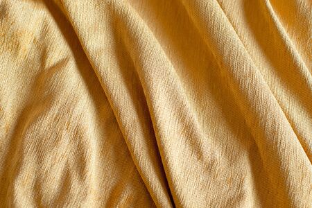 Mustard crumpled material for background or texture, tablecloth on a wooden tableの写真素材