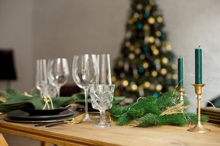 Christmas decoration with pine branches, table setting and candles on a dark Christmas tree backgroundの写真素材