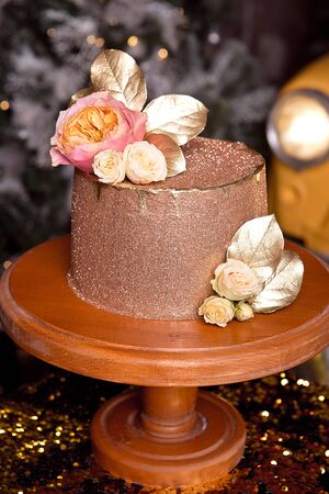 Chocolate cake with raspberry filling and pistachio cream, decorated with roses and golden jelly sparkles in the New Years interiorの写真素材