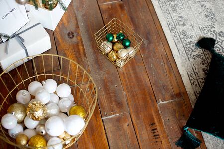 Christmas gift boxes on a wooden floor near a Christmas tree and a green sofa.の写真素材