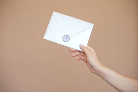 Close-up photo of female hands with wax seal with invitation envelope, gift certificate, postcard, wedding invitation cardの写真素材