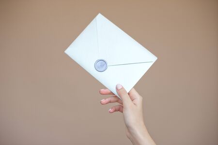 Close-up photo of female hands with wax seal with invitation envelope, gift certificate, postcard, wedding invitation cardの写真素材