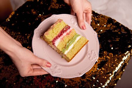 Golden brilliant tasty cake is cut into pieces. A slice of cake on a pink plate. Homemade baking for a children's party.の写真素材