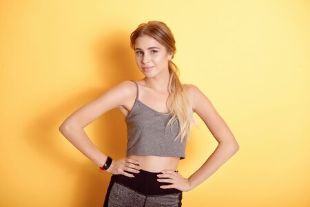 Young caucasian woman wearing in sports bra over isolated background smiling with hands on hips with closed eyes and gesture on face dreaming about happinessの写真素材