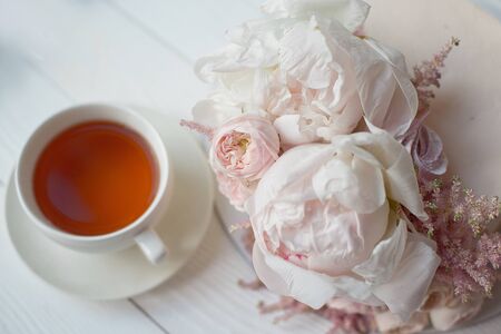Decorated with fresh flowers, a white nude cake, a stylish cake for weddings, birthdays and events a white cup with a hot drink.の写真素材