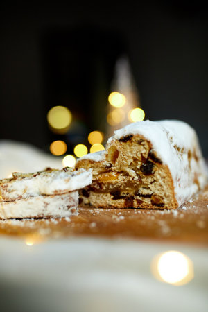 Homemade traditional marzipan Christmas Stollen on white background, with christmas lights and decorationsの写真素材