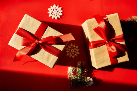 Top view Christmas eco friendly packaging kraft paper and fir branches gifts for the Holiday season on red background, hard lightの写真素材