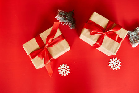 Top view Christmas eco friendly packaging kraft paper and fir branches gifts for the Holiday season on red background, hard lightの写真素材