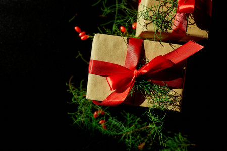 Top view  Christmas eco friendly packaging kraft paper and fir branches gifts for the Holiday season on black backgroundの写真素材