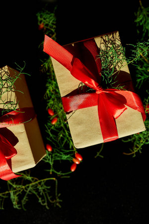 Top view  Christmas eco friendly packaging kraft paper and fir branches gifts for the Holiday season on black backgroundの写真素材