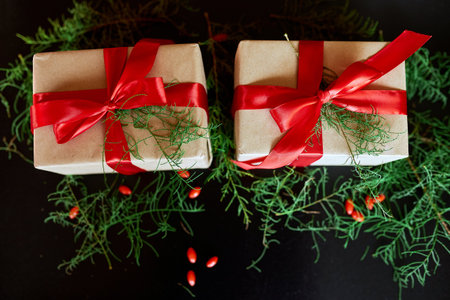 Top view  Christmas eco friendly packaging kraft paper and fir branches gifts for the Holiday season on black backgroundの写真素材