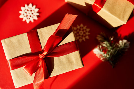 Top view Christmas eco friendly packaging kraft paper and fir branches gifts for the Holiday season on red background, hard lightの写真素材