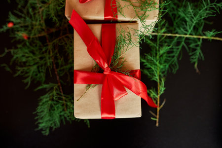 Top view  Christmas eco friendly packaging kraft paper and fir branches gifts for the Holiday season on black backgroundの写真素材