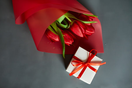 Top view red tulips flowers in red paper wrapper with gift box, festive background, concept of Happy Mother's day, Woman's day, birthday, 8 March, Valentines dayの写真素材