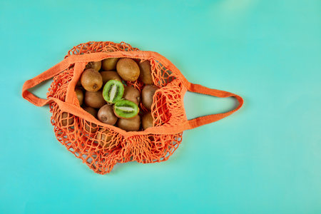 Flat lay Mesh grocery  shopping eco friendly bag with kiwi on blue canvas background, Zero waste cconcept, Local farmers market, shopping mall, top view, copy space, Plastic free items.の写真素材