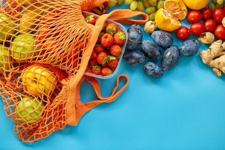 Flat lay Mesh grocery shopping eco friendly bag with fruits on blue canvas background, Zero waste cconcept, Local farmers market, shopping mall, top view, copy space, Plastic free items.の写真素材