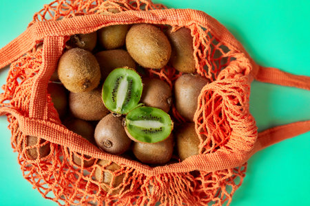 Flat lay Mesh grocery  shopping eco friendly bag with kiwi on green canvas background, Zero waste cconcept, Local farmers market, shopping mall, top view, copy space, Plastic free items.の写真素材