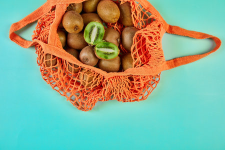 Flat lay Mesh grocery  shopping eco friendly bag with kiwi on blue canvas background, Zero waste cconcept, Local farmers market, shopping mall, top view, copy space, Plastic free items.の写真素材