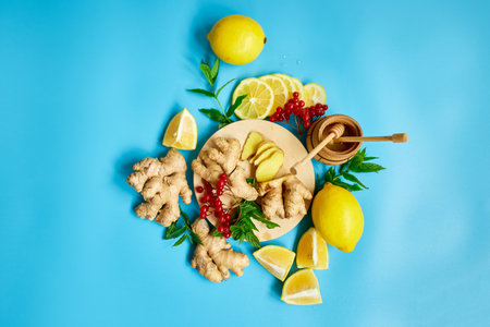 Flat lay of Immune boosting remedy, immunity boosting foods ginger, lemon,  honey,  guelder rose, mint on blue background Top view, copy spaceの写真素材