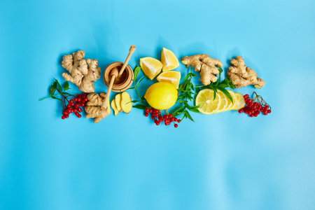 Flat lay of Immune boosting remedy, immunity boosting foods ginger, lemon,  honey,  guelder rose, mint on blue background Top view, copy spaceの写真素材