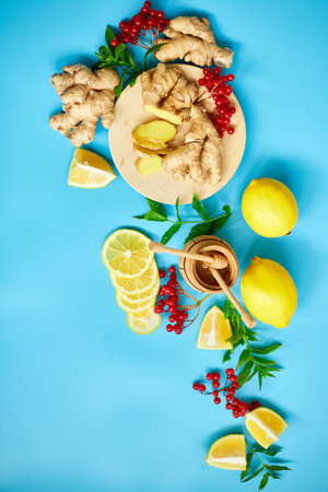 Flat lay of Immune boosting remedy, immunity boosting foods ginger, lemon,  honey,  guelder rose, mint on blue background Top view, copy spaceの写真素材