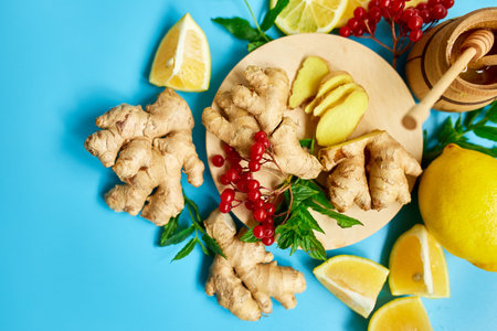 Flat lay of Immune boosting remedy, immunity boosting foods ginger, lemon,  honey,  guelder rose, mint on blue background Top view, copy spaceの写真素材