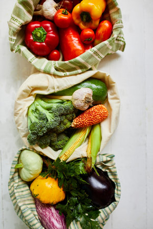 Top view assorted fresh vegetables in reusable cotton bags on table in the kitche in sunlight, groceries in textile Zero waste bags, Online grocery healthy shopping, vegan food.の写真素材