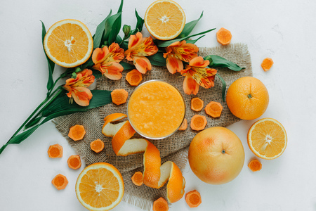 Female hands holding orange smoothie decorated with alstroemeria with orange pieの写真素材
