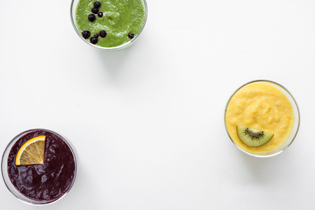 Healthy red, orange, green, yellow and pink Smoothies and juices in bottles. Grey concrete background with fresh organic vegetables, fruits and berries ingredients, top viewの写真素材
