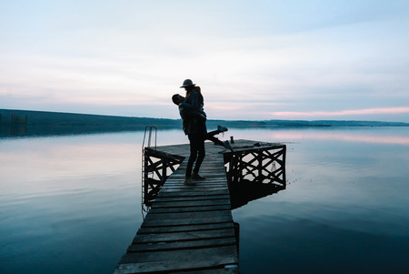 Young beautiful couple in love holding and kissing on the beach on sunset. Soft sunny colors.の写真素材