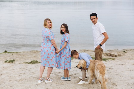 happy young family have fun and play with beautiful dog at vacations on beautiful beachの写真素材