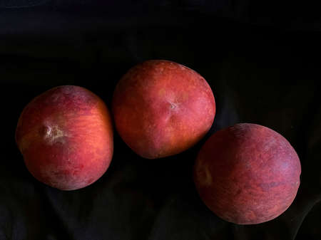 Three peaches on a black background. Photography of fruits, low key photo.の写真素材