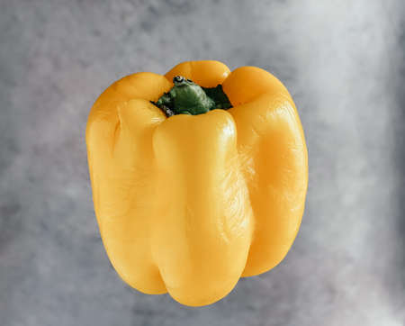 Sweet bell pepper yellow levitating in the air on a gray marble background. Healthy food and...
