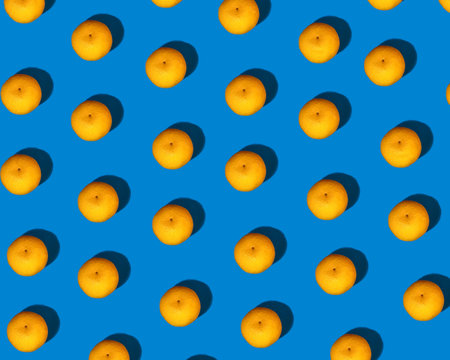 A pattern of little bright orange mandarins with a pronounced shadow on a bright blue background....