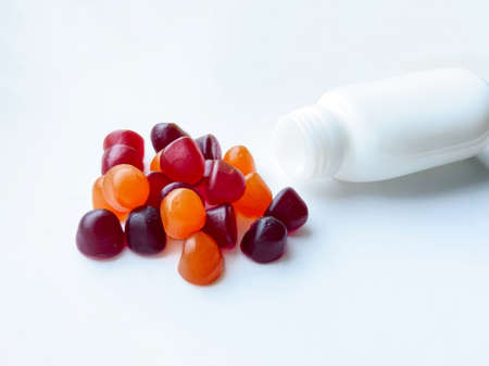 Group of red, orange and purple multivitamin gummies with the bottle isolated on white background. Healthy lifestyle concept.の写真素材