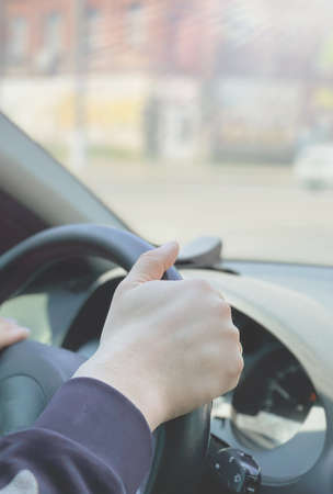 A man driving a car passing by a city landscapeの写真素材