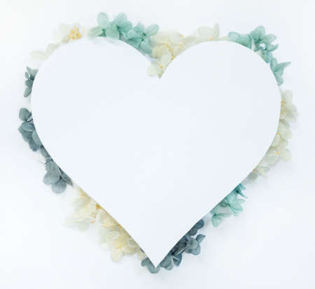 Flowers composition from blue and yellow flowers in the form of a heart on white background. Spring, summer template for your projectsの写真素材