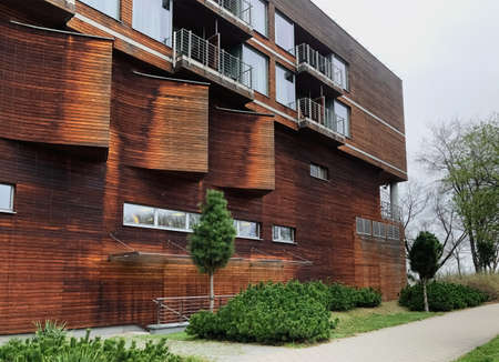 A beautiful wooden apartment building with a well-groomed territory near in summer time against a...