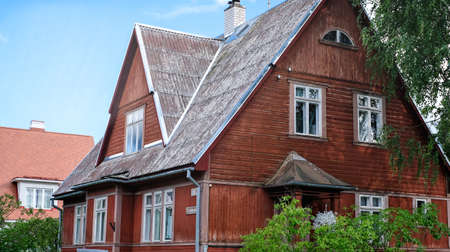 A private house of two floors with triangular roof and an area near the house against a blue skyの写真素材