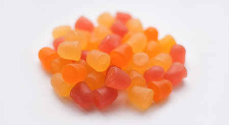 Selective focus, close-up texture of orange and yellow multivitamin gummies on white background