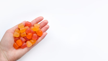 Group of red, orange and yellow multivitamin gummies in the hand isolated on white backgroundの写真素材