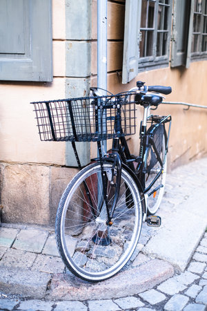 Walking black bicycle with a basket parked to a pillar in the cityの写真素材