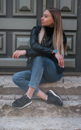 Beautiful caucasian girl with blond hair in a black jacket and blue jeansの写真素材