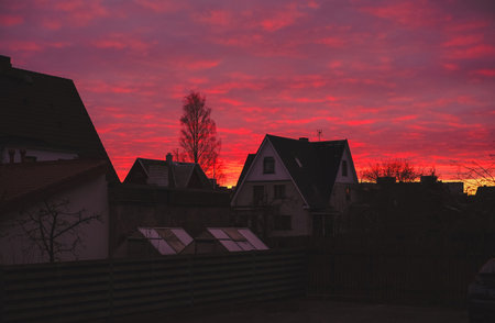 A white houses with a red sunset is in front. The house is surrounded by treesの写真素材