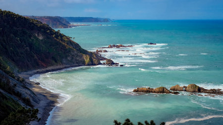 Panoramic view of a rugged coastline with turquoise sea, dramatic cliffs, and rock formations
