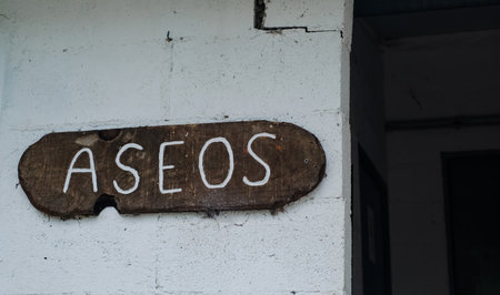 Rustic wooden sign with the Spanish word ASEOS handwritten in white paint, meaning toilets or restroomsの写真素材