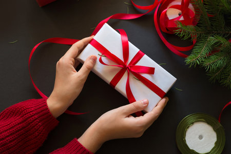 Christmas gift in hands on dark table backgroundの写真素材