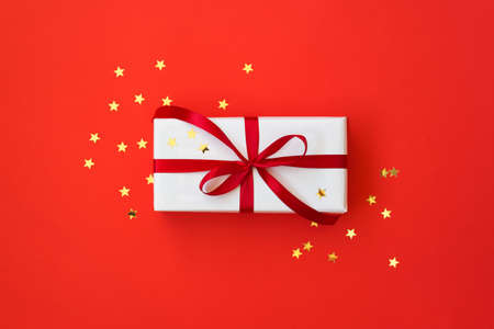 Christmas background with gift box and golden stars over red backdrop.の写真素材